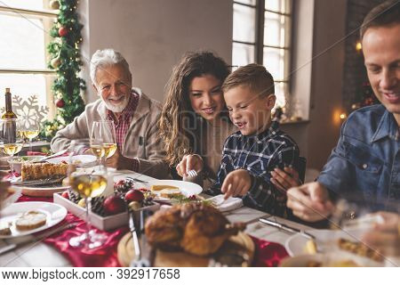 Beautiful Happy Family Having Fun Celebrating Christmas At Home, Gathered Around The Table, Having C