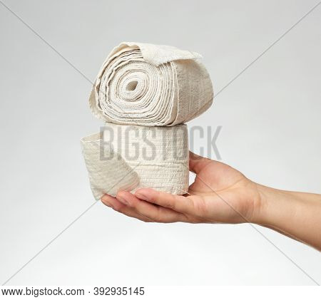Woman Holds In Hand A White Elastic Bandage For The Body, Gray Background