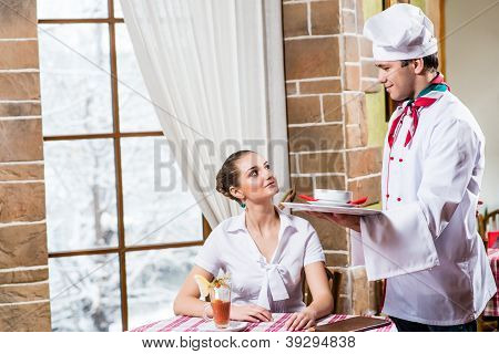 Lo chef porta una donna abbastanza piatto in un ristorante
