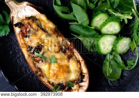 Stuffed Eggplant Half With Melted Cheese, Mushroom And Vegetables Roasted And Served On The Black Pl