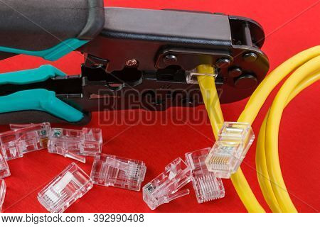 Computer Network Laying Concept. Crimper Tool And Transparent Connectors Connectors On Red Backgroun