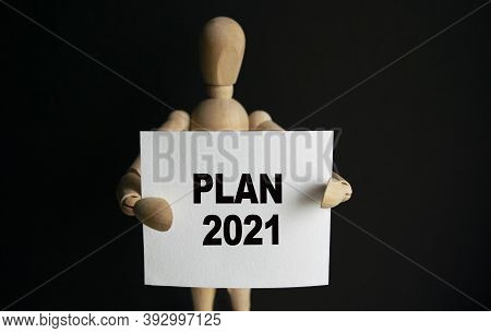 The Wooden Man Holds A White Sign With The Text Plan 2021 In His Hands. The Content Of The Lettering