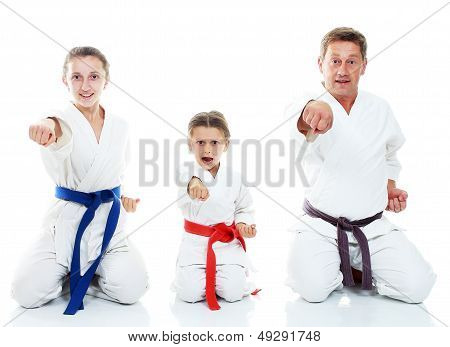 Dad and his daughters sitting in a ritual pose karate and beat his fist on a white background