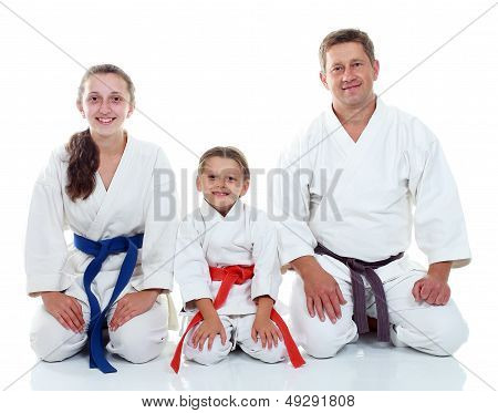 Dad with his daughters in kimono sitting in a ritual pose Karate