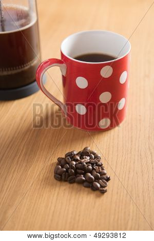 Kaffebønner, kaffemaskine og røde pletter krus