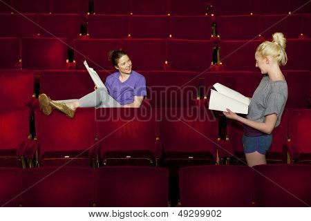 Duas mulheres jovens sentado no teatro empata com scripts