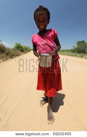 MORONDAVA, MADAGASCAR - DECEMBER 08 Portrait of unidentified smiling girl with can, December 08, 2013, Morondava region, Madagascar. Children in Madagascar are friendly and often barefoot.