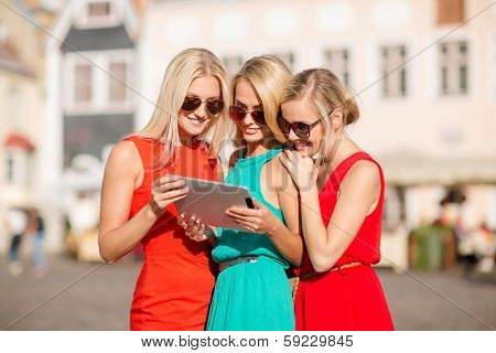 holidays and tourism concept - beautiful blonde girls toursits looking into tablet pc in the city