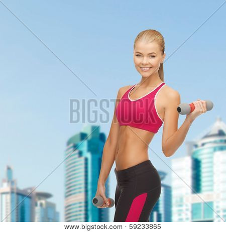 fitness and dite concept - young sporty woman with light dumbbells