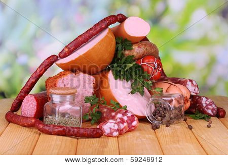 Lot of different sausages on wooden table on natural background