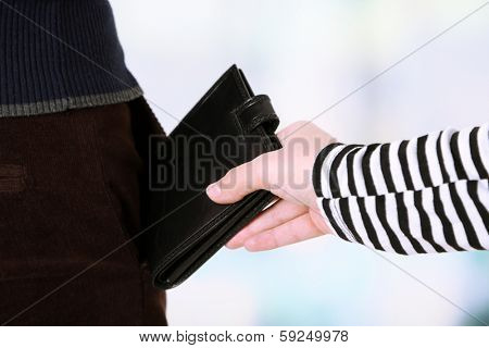Pickpocket are stealing wallet from pocket, close up, on light background