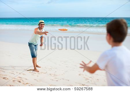 Father and son playing frisbee at beach