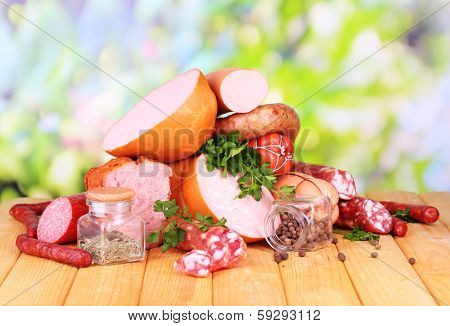 Lot of different sausages on wooden table on natural background