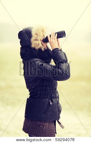 Woman standing outside and holding lorgnette in cold winter day.