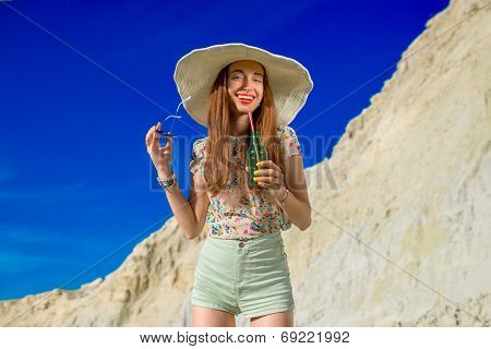 Young Woman Drinking From The Bottle On The Sky Background On The Summer