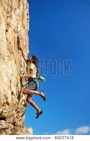 A rock climbing man reaching for a grip on a steep mountain in the outdoors