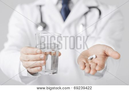 picture of doctor hands giving white pills and glass of water