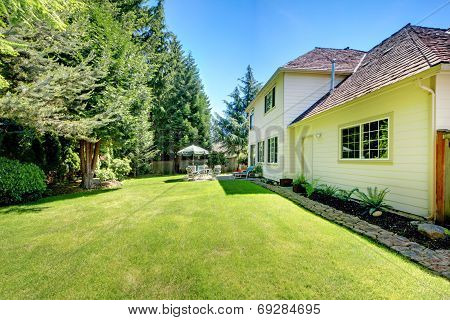Suny Green Backyard With Yellow Hosue.