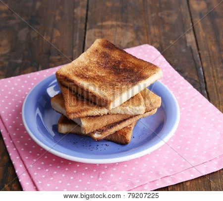 Toast bread on blue plate with pink napkin, on wooden table background
