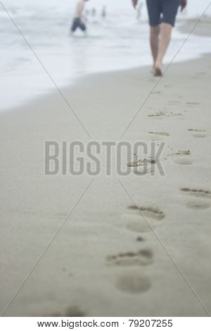 Legs Of Man And Footprints On Sand Of Beach