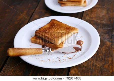 Toast bread with chocolate on plate with knife on wooden table background