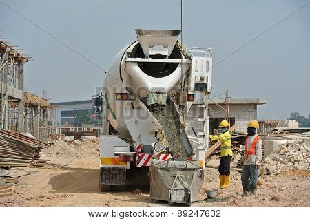 Group of construction workers pouring concrete from concrete mixer