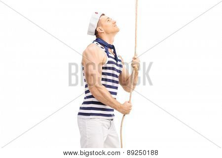 Handsome young sailor pulling a rope and looking up isolated on white background