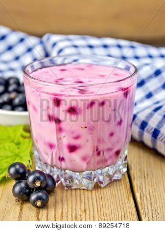 Milkshake with black currants in glass on board