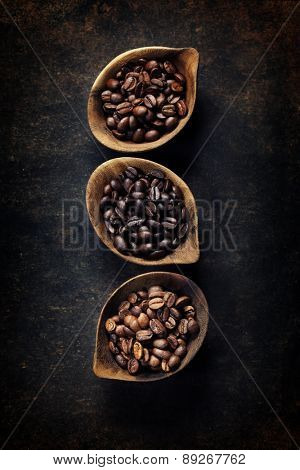 Top view of three different varieties of coffee beans on dark vintage background