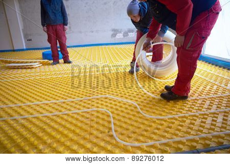 grouo of workera installing underfloor heating and colling in modern home
