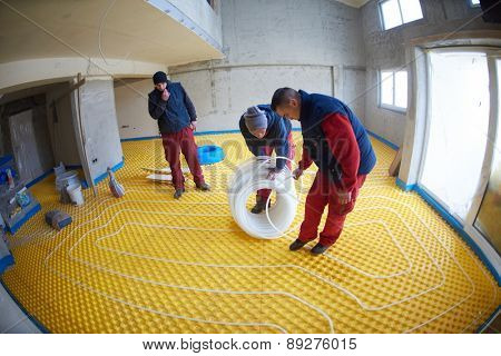 grouo of workera installing underfloor heating and colling in modern home