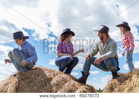 cowboy family of four sitting on haystacks