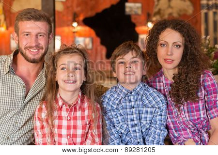 family of four closeup portrait on background of wall with pelts and photos