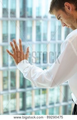 Young caucassian businessman standing against office window