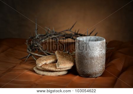 Communion cup and bread with crown of thorns in background