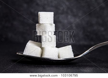 Cloose Up White Sugar Cubes In Metal Spoon On Black Stone Plate Background
