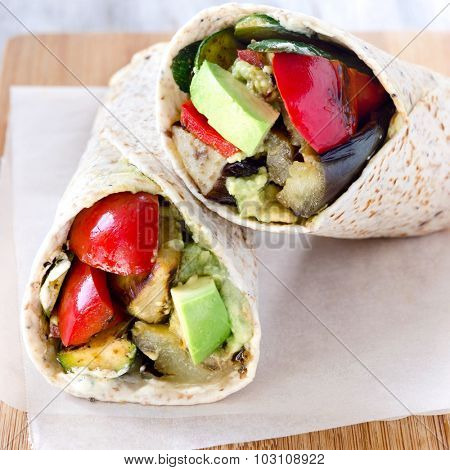 Healthy vegetarian vegan burrito wraps with roasted vegetables like aubergine eggplant, red bell peppers, avocado 