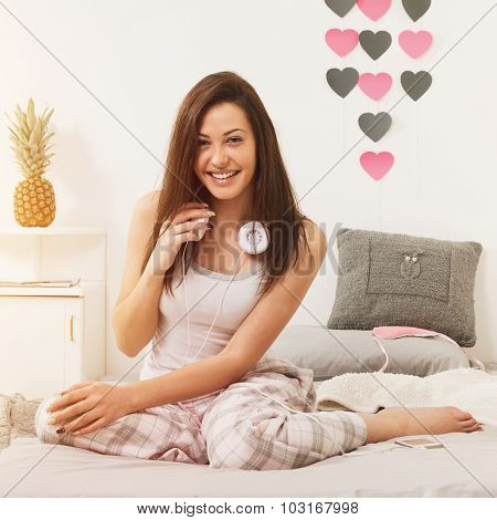 Young woman with headphones relaxing in bed in the morning