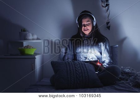 Teenage girl watching movie on tablet in bed at night
