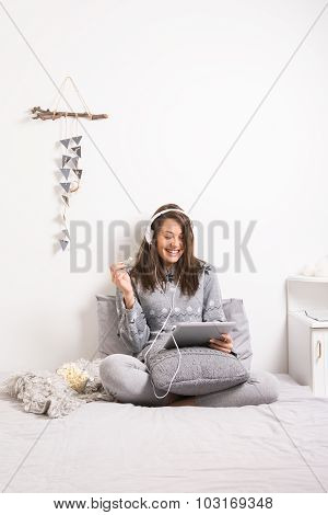 Young brunette woman relaxing watching movie in bed