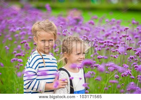 Little adorable girls walking outdoors with flowers