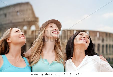 summer holidays, people, travel, tourism and vacation concept - group of smiling young women over coloseum in Rome background