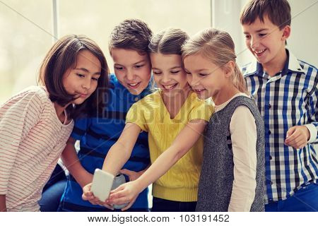 education, elementary school, drinks, children and people concept - group of school kids taking selfie with smartphone in corridor