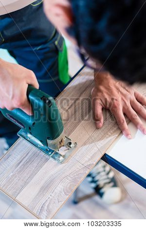 DIY worker cutting wooden panel with jig saw