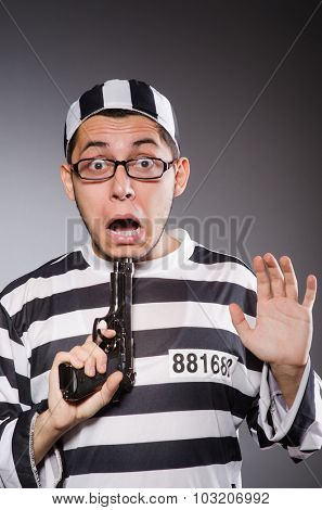 Young prisoner with weapon against gray