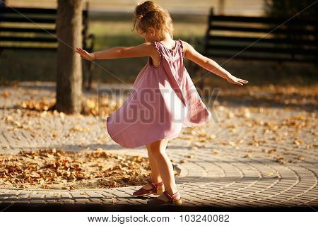 Full Length Portrait Of A Little Girl Dancing In The Park A Warm Autumn Evening. In Move