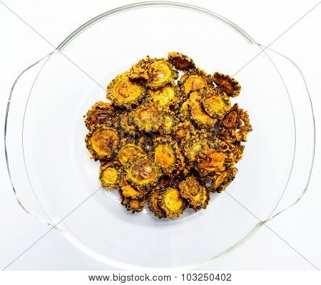 Tasty fried bittergourd chips kept on a glass bowl on a plain background