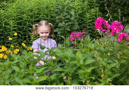 Little Girl With Tails Among Flowers In The Park