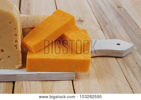 various types of fresh raw aged delicatessen cheese on white plate over light wooden table cheddar edam swiss
