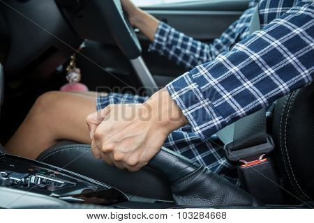 Closeup Of Young Woman Pulling Handbrake Lever In Car